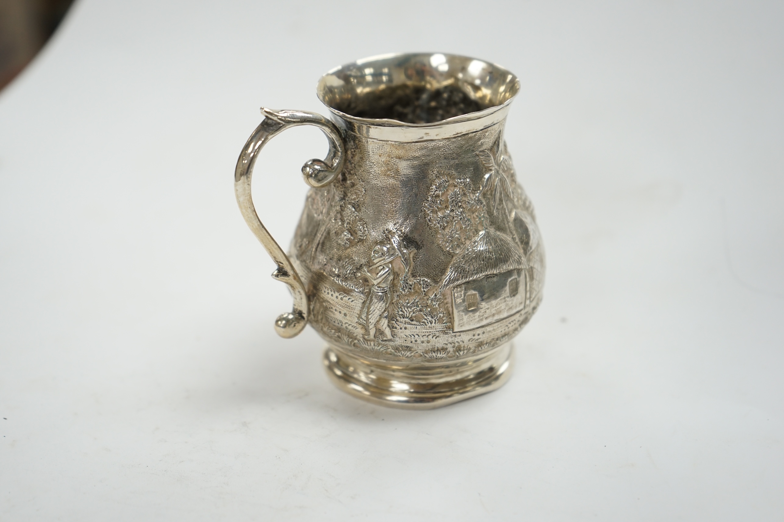 An Indian embossed white metal baluster mug, height 77mm, 94 grams. Condition - poor to fair